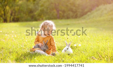 the girl sitting on the sunny lawn among the rabbits