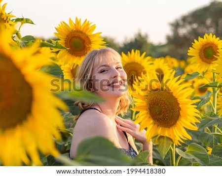 A pretty joyful lady spending free time in the summer sunflower field