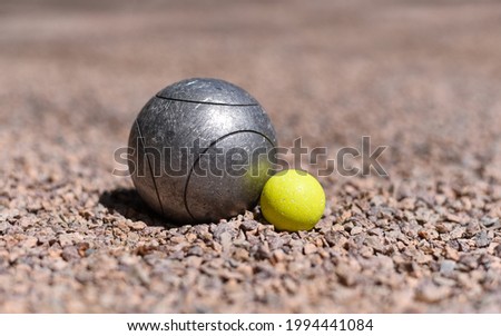 A petanque ball (boule) close to a yellow jack target ball on a pink gravel petanque ground. Royalty-Free Stock Photo #1994441084