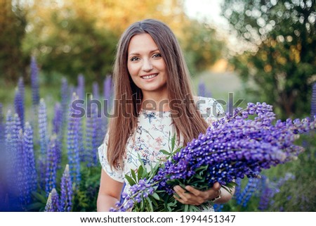 Beautiful young girl with bouquet in the lupine fields