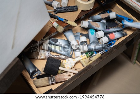 Drawer,cabinet of the artist, painter with scattered, disordered paints in a tube, paint brushes standing by the canvas, artistic mess in the paint store, in the studio.