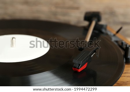 Vinyl record on turntable against blurred background, closeup