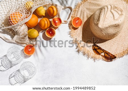 Summer fashion flat lay on white background. Holiday party, vacation, travel, tropical concept. Straw hat, sunglasses, glass and citrus fruits. Palm shadow and sunlight, sun. Top view, copy space Royalty-Free Stock Photo #1994489852