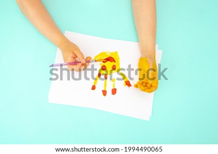 Children's pens draw with bright colors on paper. Children's handprint