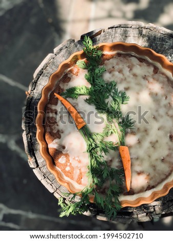 Carrot cake with sugar icing in ceramic mold on wooden hemp