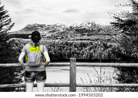 Young woman (unrecognizable back view) admiring view of lake Pavin in Auvergne Volcanic Regional Nature Park, France. Hiking, lifestyle. Black white yellow vintage toned photo. Retro travel background