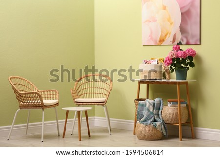 Modern hallway interior with beautiful hortensia flower on console table near wicker armchairs