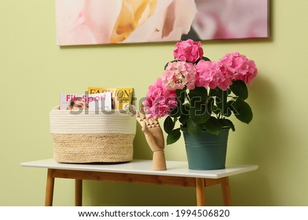 Console table with beautiful hortensia flower near light green wall in hallway. Interior design