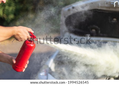 A man that use a fire extinguisher to turn off the fire from the car engine   Royalty-Free Stock Photo #1994526545