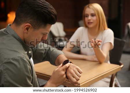 Man getting bored during first date with overtalkative young woman at outdoor cafe Royalty-Free Stock Photo #1994526902