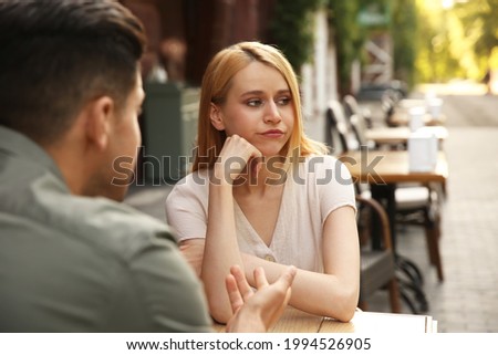 Young woman getting bored during first date with man at outdoor cafe Royalty-Free Stock Photo #1994526905