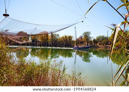 Ravenna, Emilia Romagna, Italy: landscape of the river with net of the fishing hut and boat in the nature reserve Po Delta Park

