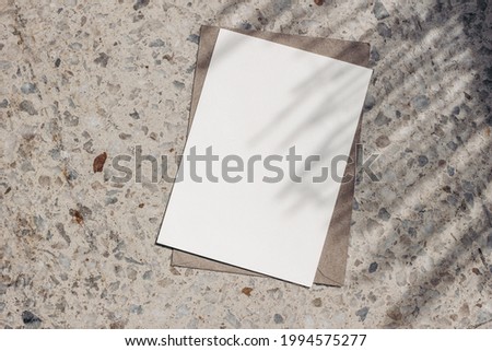 Blank greeting card, invitation mockup in sunlight. Terrazzo background. Marble stone texture, palm tree leaf shadow overlay. Modern template, branding identity. Summer vacation design. Flat lay, top Royalty-Free Stock Photo #1994575277