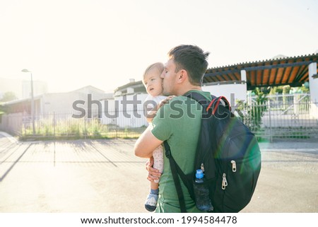 Daddy kisses and holds a little girl in front of the park gate