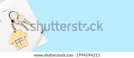 Keys and house keychain on real estate mortgage loan document, contract agreement to buy or construction new home, insurance, registration of lease, rent apartments. Blue banner background, copyspace. Royalty-Free Stock Photo #1994594213