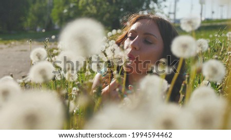 pretty curly woman will enjoy a warm summer day in a field of dandelions