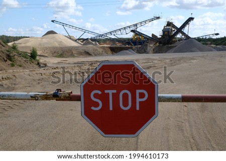 Quarry aggregate with heavy duty machinery,  standing among heaps of sand and barrier with a STOP sign