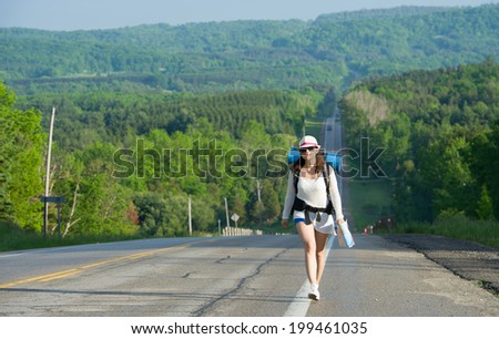 girl with backpack walking on the road 