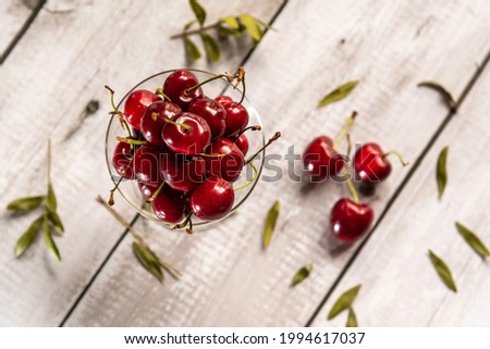 Red cherries in glass cup on wooden table