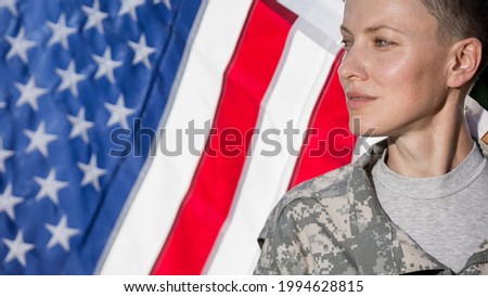 portrait of an american woman soldier saluting over us flag waving
