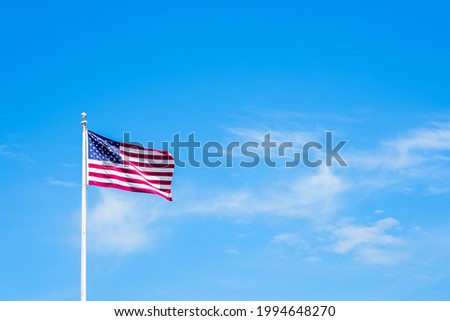 Amaerican flag on pole with blue sky and whiteclouds