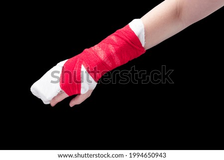 Broken arm with white gypsum and red bandage isolated on black background