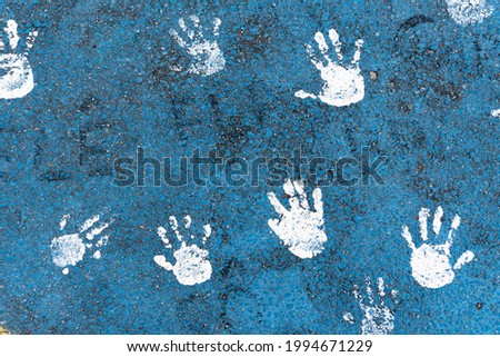 Drawing of children's hands painted on the asphalt in blue and white colors. Alphast texture and paint colors.