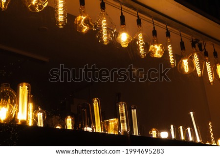 Row of different electric retro hanging lamp bulbs. Dark background. Warm yellow light