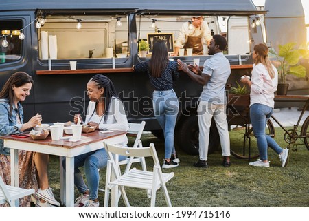 Multiracial people eating food truck gourmet food outdoor - Healthy meal, summer and dinner concept - Focus on african woman face Royalty-Free Stock Photo #1994715146