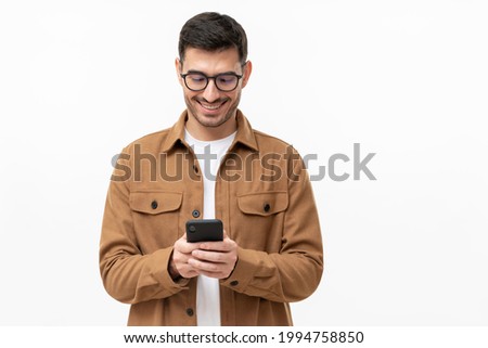 Young man looking at phone, standing isolated on gray background