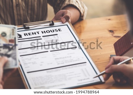 Following a deal with a broker, A Man signs a contract to rent a house.