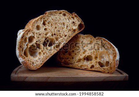 A loaf of rye bread cut in half on a wooden cutting board. Homebaked bread . Royalty-Free Stock Photo #1994858582