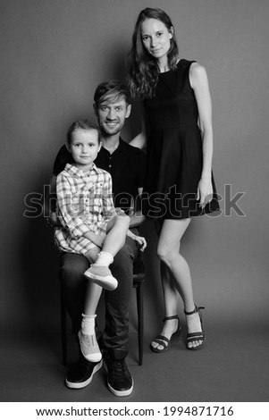 Studio shot of young Russian family bonding together against gray background in black and white