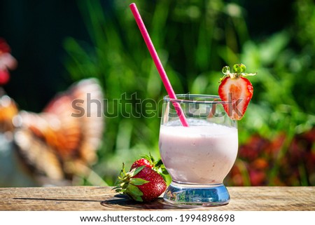 Milkshake with strawberries in a glass with a close-up tube.