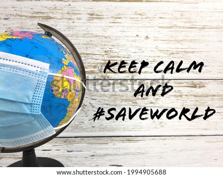 Globe with facemask. Describe the current global situation during pandemic season. Written Keep Calm and #saveworld on background. Selective focus. 
