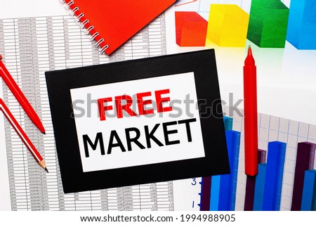 Reports and color charts are on the table. There are also red pens, pencil and paper in a black frame with the words FREE MARKET. View from above