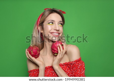 Young woman with fresh pitahayas on green background. Exotic fruits