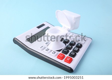 Calculator and minim model of the toilet on a blue background. Draining the budget