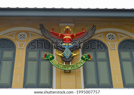Emblem of Thailand on the wall of the house. Underneath the emblem the phrase "By Appointment to His Majesty the King".