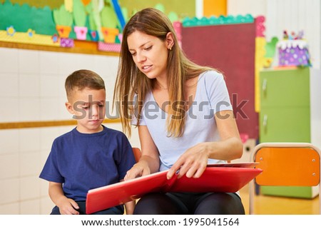 Kindergarten teacher or childminder reading a book for a child in kindergarten or after-school care center