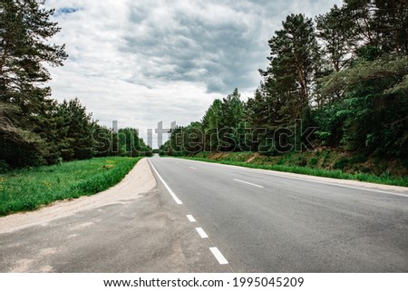 Empty country asphalt road near forest in summer time.
