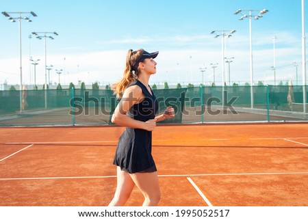 A beautiful young woman runs around in the stadium. Tennis court, professional athlete in a dress suit. burning before practice. Prepare for a game. Active lifestyle, fitness body, outdoor.
