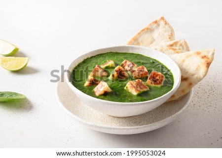 Palak Paneer with chapati on white background. Indian vegetarian cuisine made of spinach and paneer cheese. Close up. Royalty-Free Stock Photo #1995053024