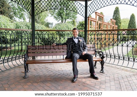 Smiling groom sitting on bench in park