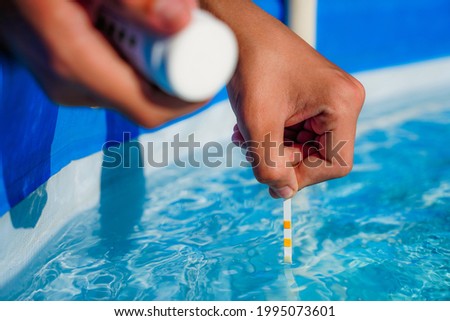 Checking the water quality of a pool with the help of a test strip with PH value, chlorine and algaecide Royalty-Free Stock Photo #1995073601
