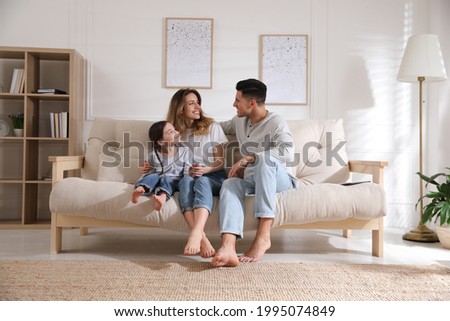 Happy family with little daughter sitting on sofa in living room Royalty-Free Stock Photo #1995074849
