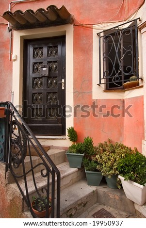  An ancient wooden carved door, a window with a figured lattice, stone steps and flowers in pots