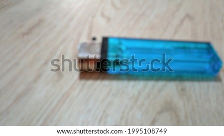 Blurred photo of Blue gas lighter was lying on the table.
