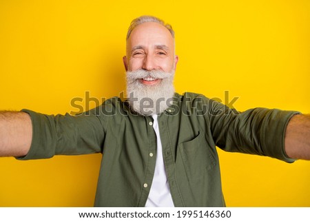 Photo portrait of grandfather taking selfie on camera smiling isolated bright yellow color background
