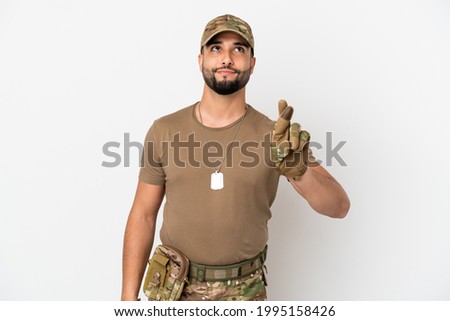 Young arab soldier man isolated on white background with fingers crossing and wishing the best